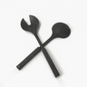 Black resin salad servers crossed together on a white background