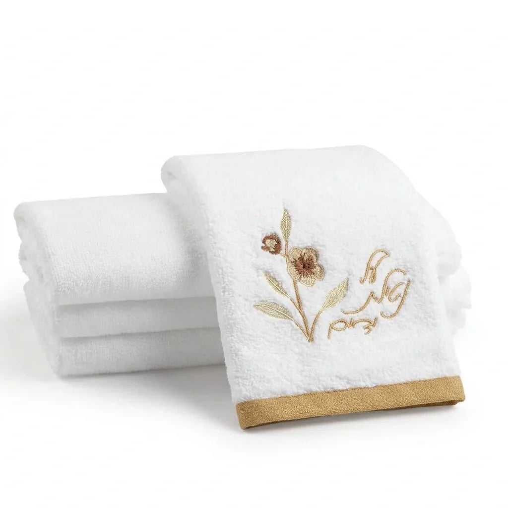 Waterdale white cotton Netilas Yadayim towel with gold floral embroidery and folded towels behind it