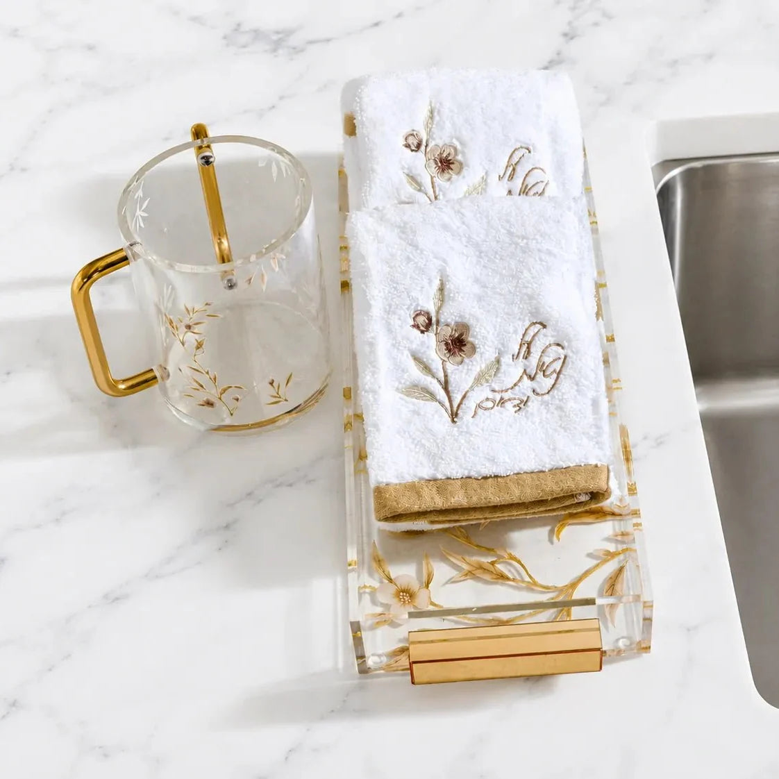 Two gold floral Netilas Yadayim towels displayed on a tray beside a floral washing cup