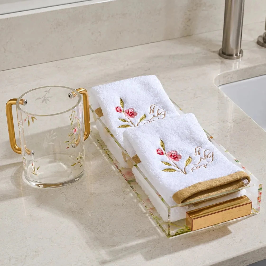 Two pink floral Netilas Yadayim towels displayed on a tray beside a floral washing cup